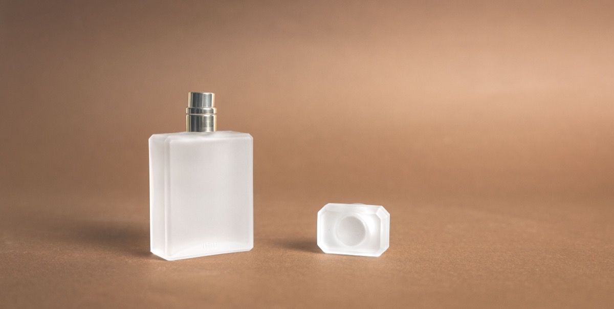 Frasco de perfume transparente e minimalista em fundo bege