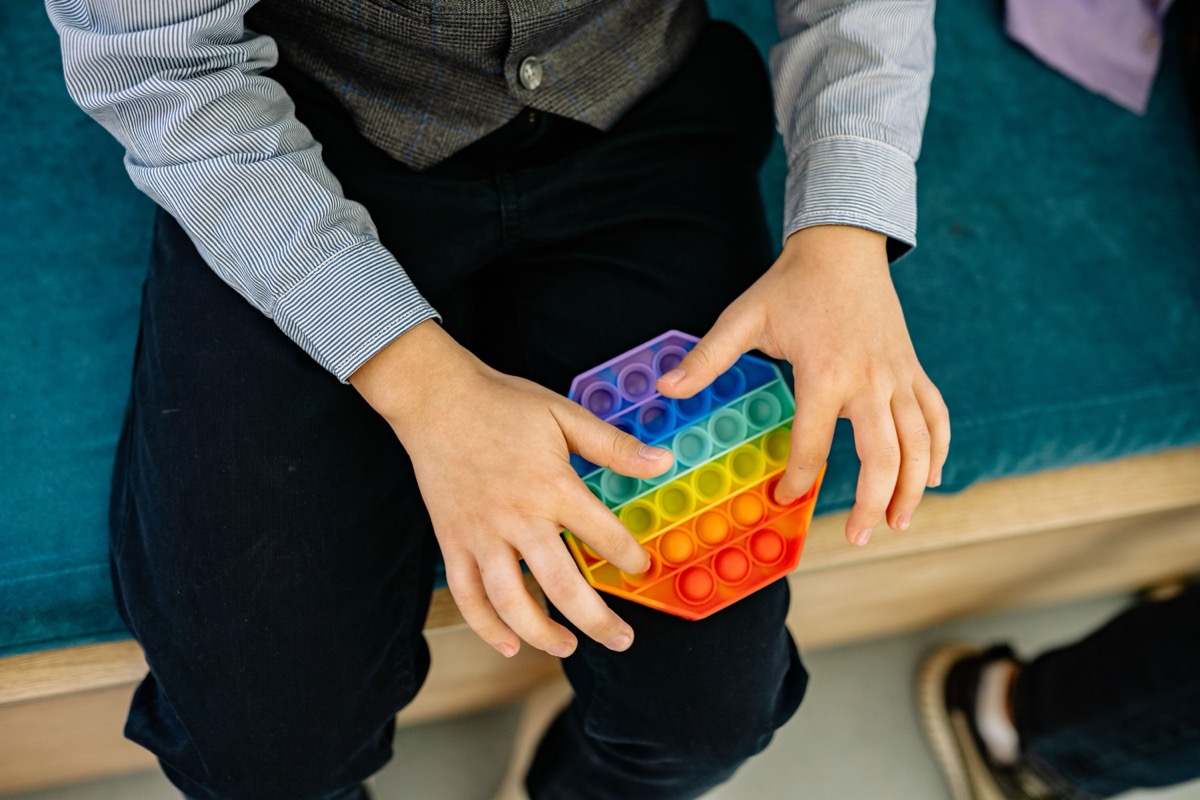 Mãos segurando um brinquedo antiestresse colorido tipo pop-it